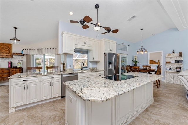 kitchen featuring visible vents, a kitchen island, vaulted ceiling, stainless steel appliances, and a sink