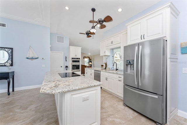 kitchen featuring light stone counters, a ceiling fan, a kitchen island, a sink, and appliances with stainless steel finishes