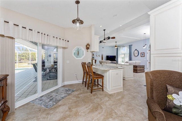 kitchen featuring decorative light fixtures, a kitchen breakfast bar, open floor plan, a peninsula, and ceiling fan