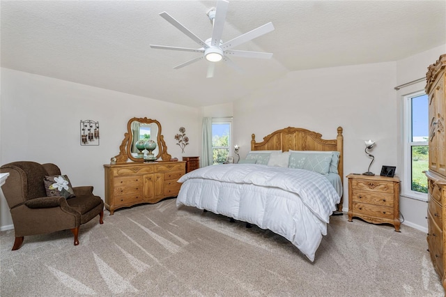 bedroom with lofted ceiling, multiple windows, light colored carpet, and a textured ceiling