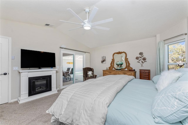 carpeted bedroom with visible vents, ceiling fan, access to exterior, vaulted ceiling, and a glass covered fireplace