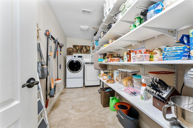 clothes washing area featuring a textured ceiling, laundry area, visible vents, and washer and clothes dryer