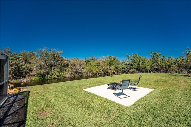 view of yard with a patio and a view of trees