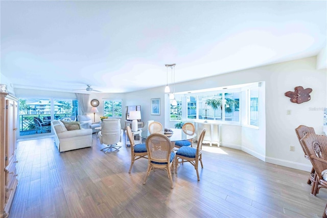 dining space with a ceiling fan, baseboards, and wood finished floors