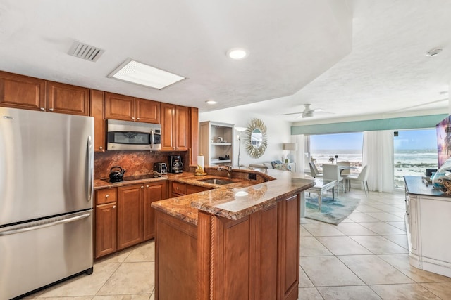 kitchen with stainless steel appliances, a peninsula, visible vents, and brown cabinets