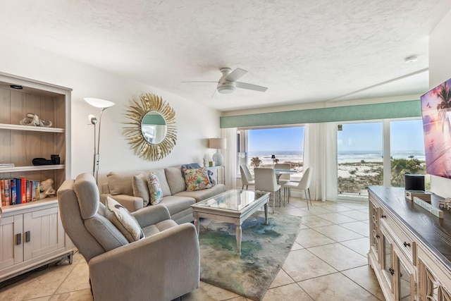 living area with a textured ceiling, light tile patterned floors, and a ceiling fan