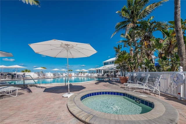 community pool featuring a hot tub, fence, and a patio