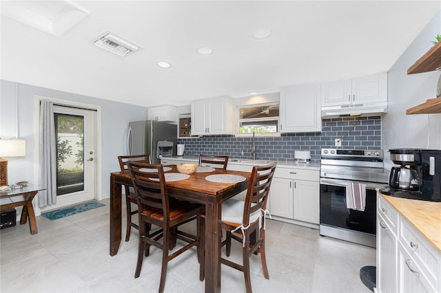 kitchen featuring under cabinet range hood, white cabinets, appliances with stainless steel finishes, open shelves, and tasteful backsplash