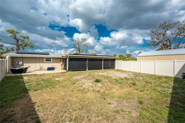 rear view of house with solar panels, a lawn, a sunroom, a patio area, and a fenced backyard