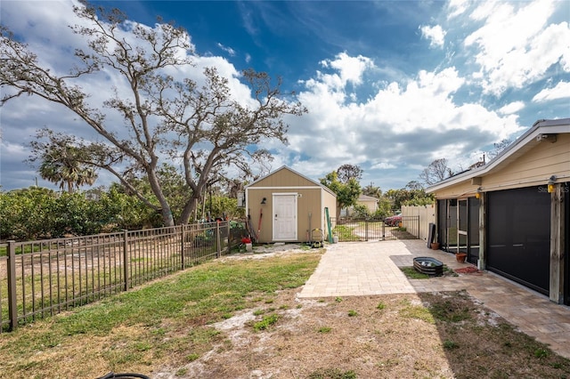 view of yard with an outbuilding, a fenced backyard, a gate, a shed, and a patio area