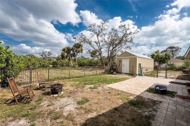 view of yard with a fire pit, a patio, a fenced backyard, an outbuilding, and a storage unit