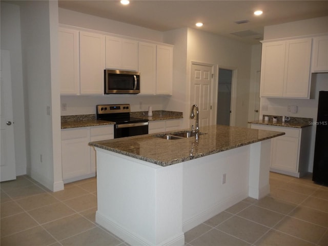 kitchen featuring light tile patterned floors, recessed lighting, stainless steel appliances, a sink, and dark stone countertops