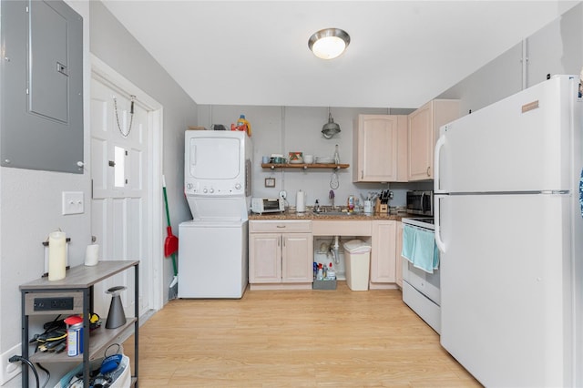 kitchen with light wood finished floors, stacked washer / drying machine, a sink, white appliances, and electric panel