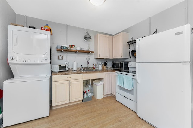 kitchen featuring open shelves, stacked washer / dryer, a sink, light wood-type flooring, and white appliances