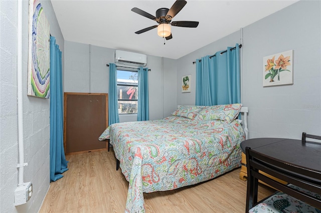 bedroom featuring a wall unit AC, light wood-style floors, and ceiling fan