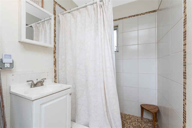 full bath featuring a shower with shower curtain, vanity, and tile walls