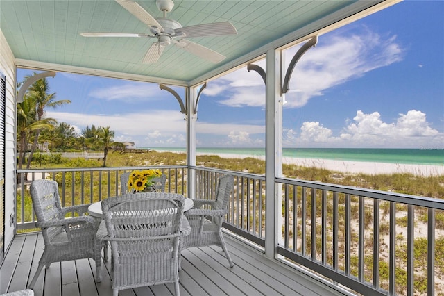 deck featuring a water view, a ceiling fan, and a view of the beach