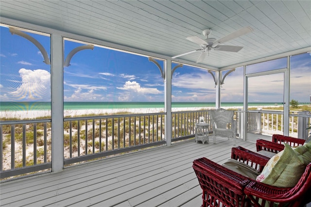 deck featuring a water view, ceiling fan, and a beach view