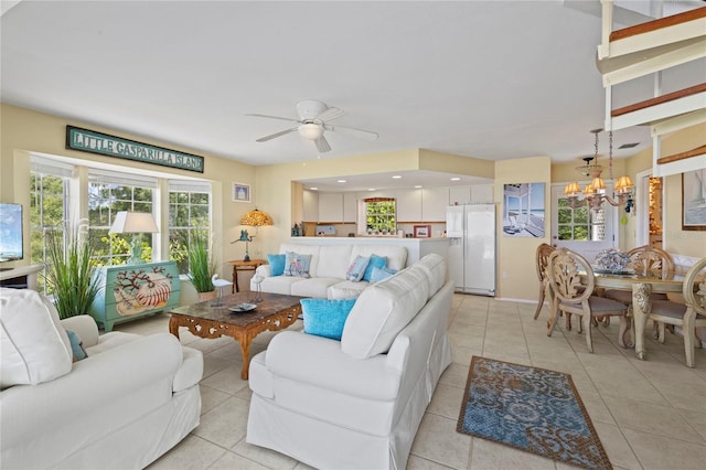 living area featuring light tile patterned flooring and ceiling fan with notable chandelier