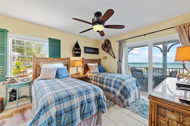 bedroom with light tile patterned floors, multiple windows, a water view, and access to outside