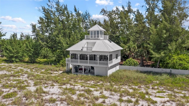 back of house featuring a standing seam roof, a sunroom, and metal roof