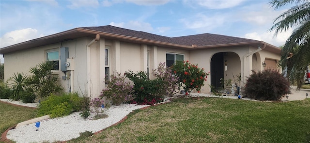 view of front of property with a garage, stucco siding, a shingled roof, and a front yard