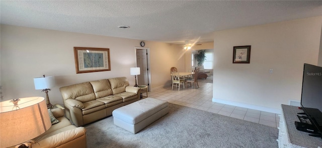 tiled living area with a textured ceiling, ceiling fan, visible vents, and baseboards