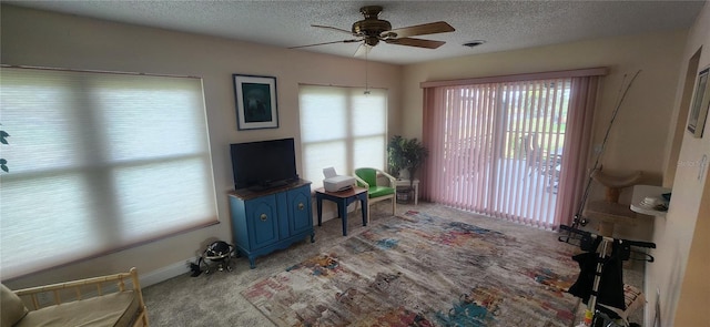 interior space featuring a textured ceiling, visible vents, carpet flooring, and a ceiling fan