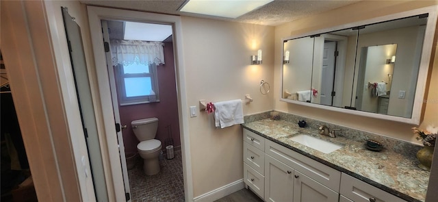 bathroom with toilet, vanity, and baseboards