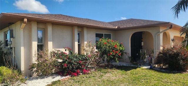 ranch-style house with stucco siding, roof with shingles, and a front yard