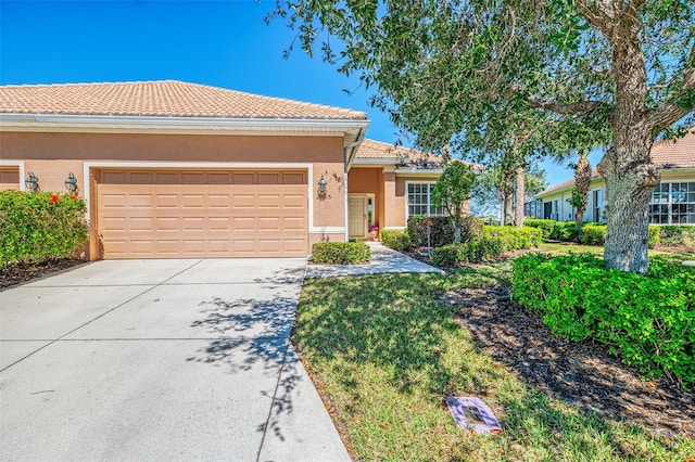 view of front of home featuring concrete driveway, a tiled roof, an attached garage, and stucco siding