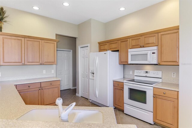 kitchen with light tile patterned floors, white appliances, a sink, and light countertops