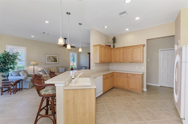 kitchen with visible vents, light brown cabinetry, a sink, open floor plan, and white appliances