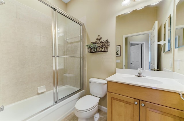 bathroom with combined bath / shower with glass door, toilet, vanity, and tile patterned floors