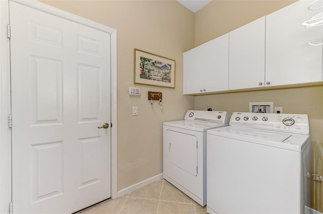 laundry area with separate washer and dryer, light tile patterned floors, cabinet space, and baseboards