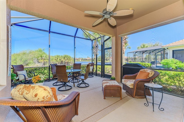 sunroom with a ceiling fan and a water view