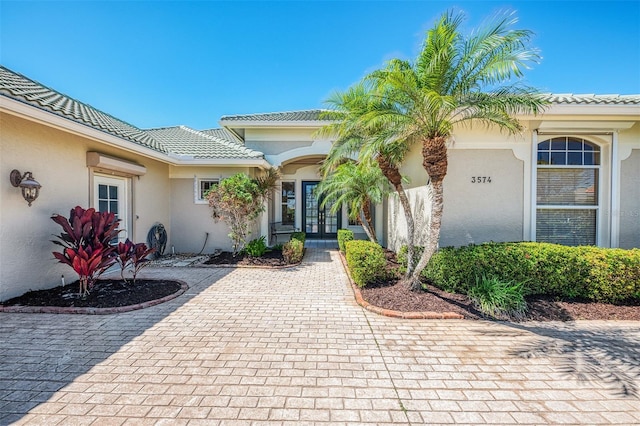 view of exterior entry featuring a tiled roof, stucco siding, and french doors