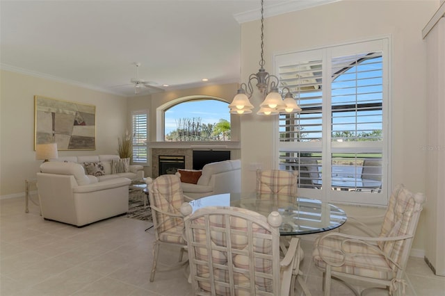 dining area featuring light tile patterned floors, a fireplace, crown molding, and baseboards