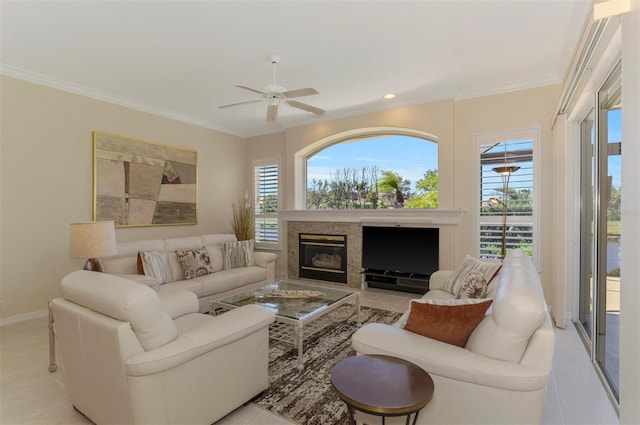 living area featuring baseboards, a ceiling fan, a healthy amount of sunlight, and crown molding