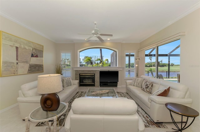 living room with baseboards, a ceiling fan, crown molding, and a water view