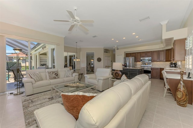 living area with light tile patterned floors, visible vents, ceiling fan with notable chandelier, and ornamental molding