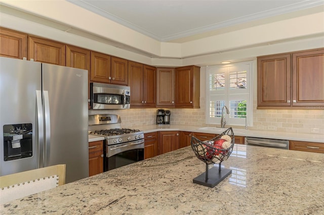 kitchen featuring ornamental molding, backsplash, appliances with stainless steel finishes, brown cabinetry, and light stone countertops