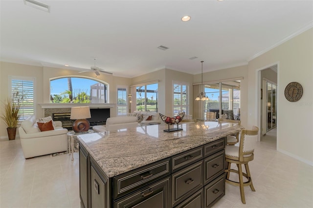 kitchen featuring visible vents, ornamental molding, a kitchen breakfast bar, and a glass covered fireplace