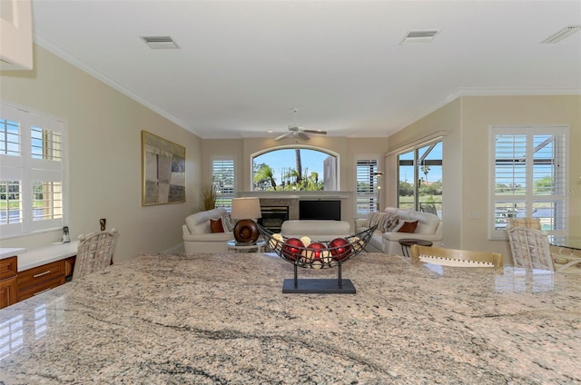 living area with a glass covered fireplace, visible vents, and a wealth of natural light