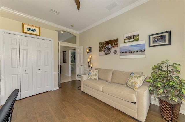 living area with baseboards, wood finished floors, visible vents, and ornamental molding