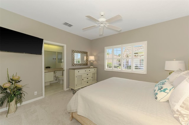 bedroom with visible vents, light carpet, a ceiling fan, connected bathroom, and baseboards