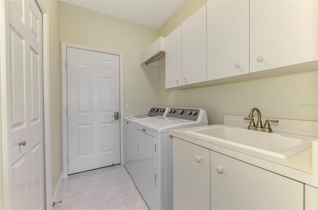 washroom featuring a sink, light tile patterned floors, cabinet space, and washer and clothes dryer