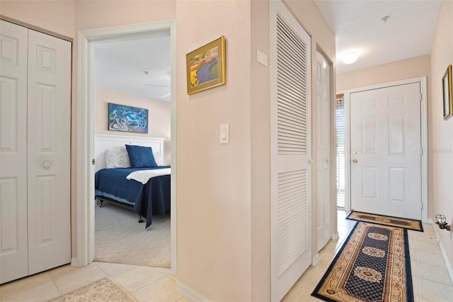 hall featuring light tile patterned flooring and light carpet