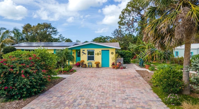 view of front of house with decorative driveway, roof mounted solar panels, and stucco siding