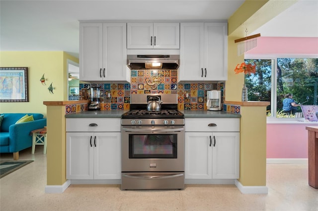 kitchen with tasteful backsplash, baseboards, dark countertops, ventilation hood, and gas stove